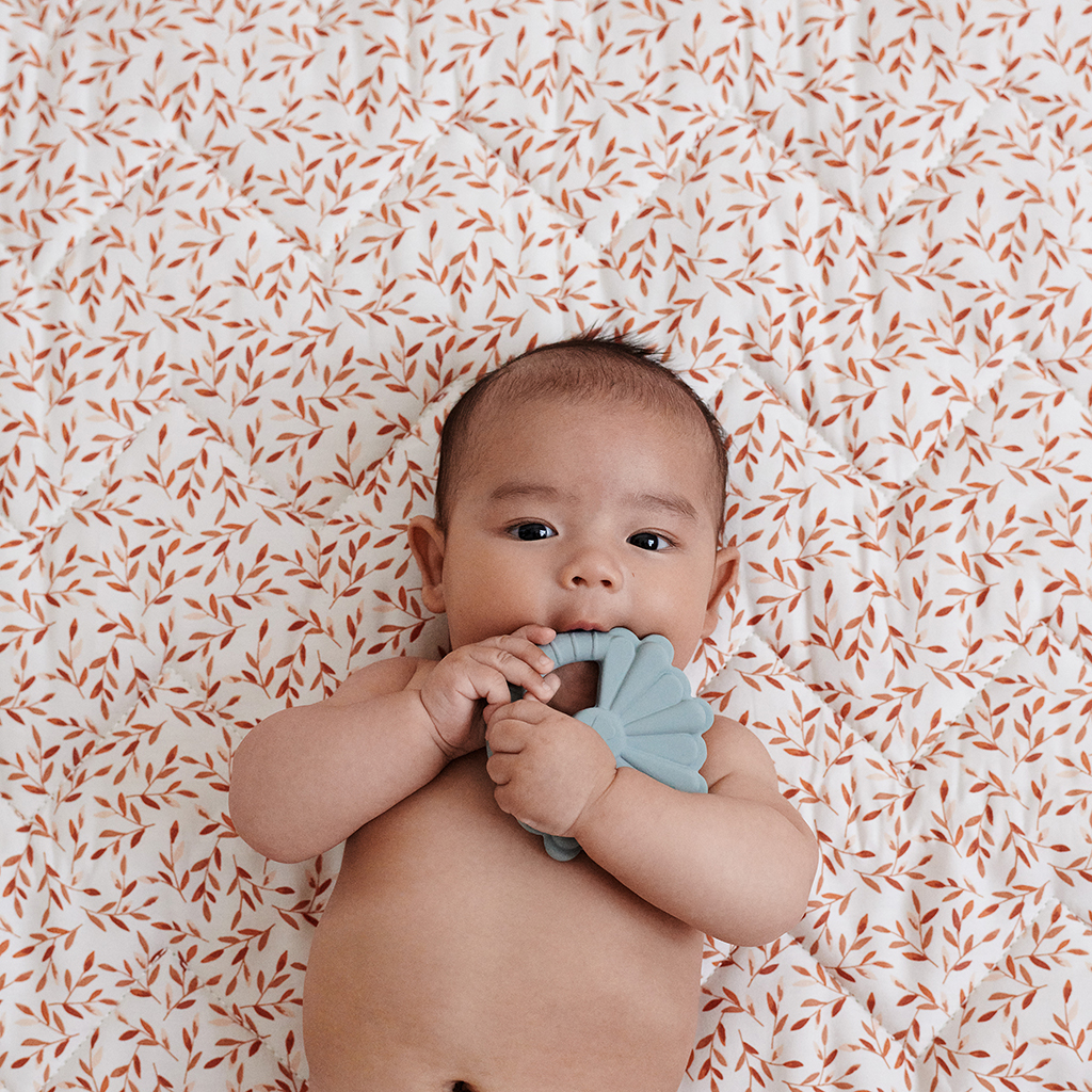 Bébé allongé tenant un jouet de dentition bleu Cam Cam Copenhagen