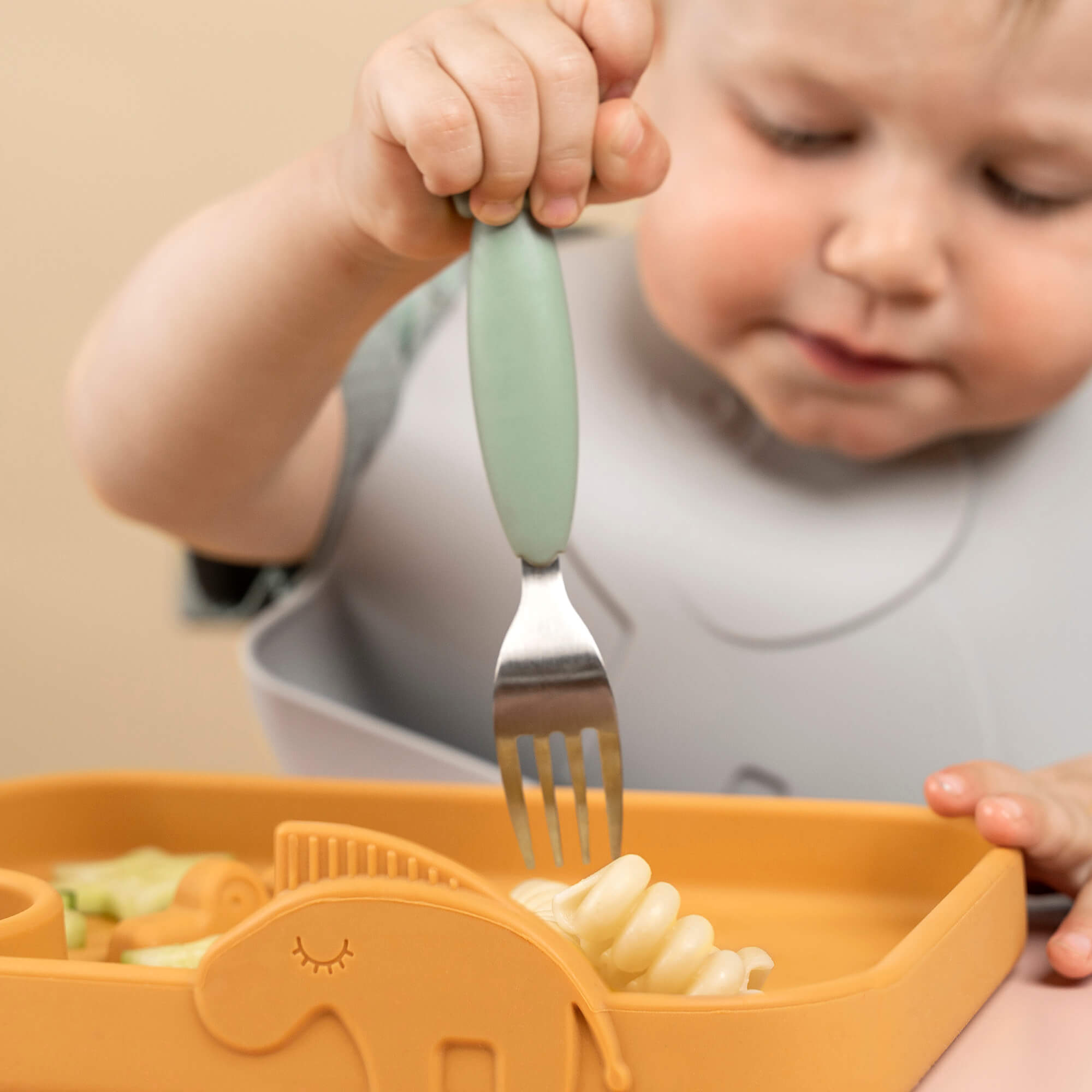 Enfant mange des pâtes avec une fourchette verte en silicone Done By Deer Easy-grip – idéale pour les repas dès 12 mois