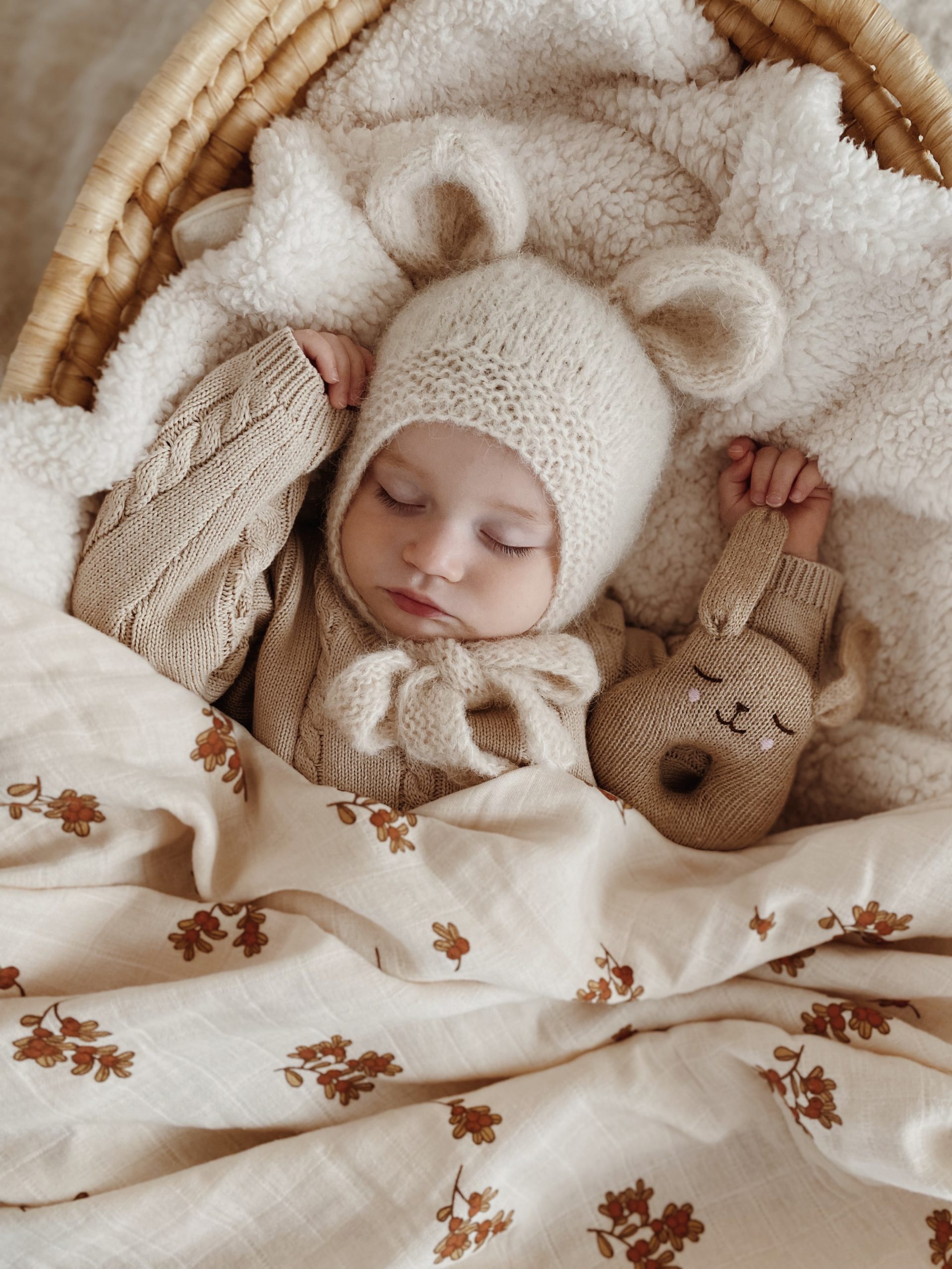 Bébé dormant dans un couffin avec le hochet lapin écru en laine Main Sauvage