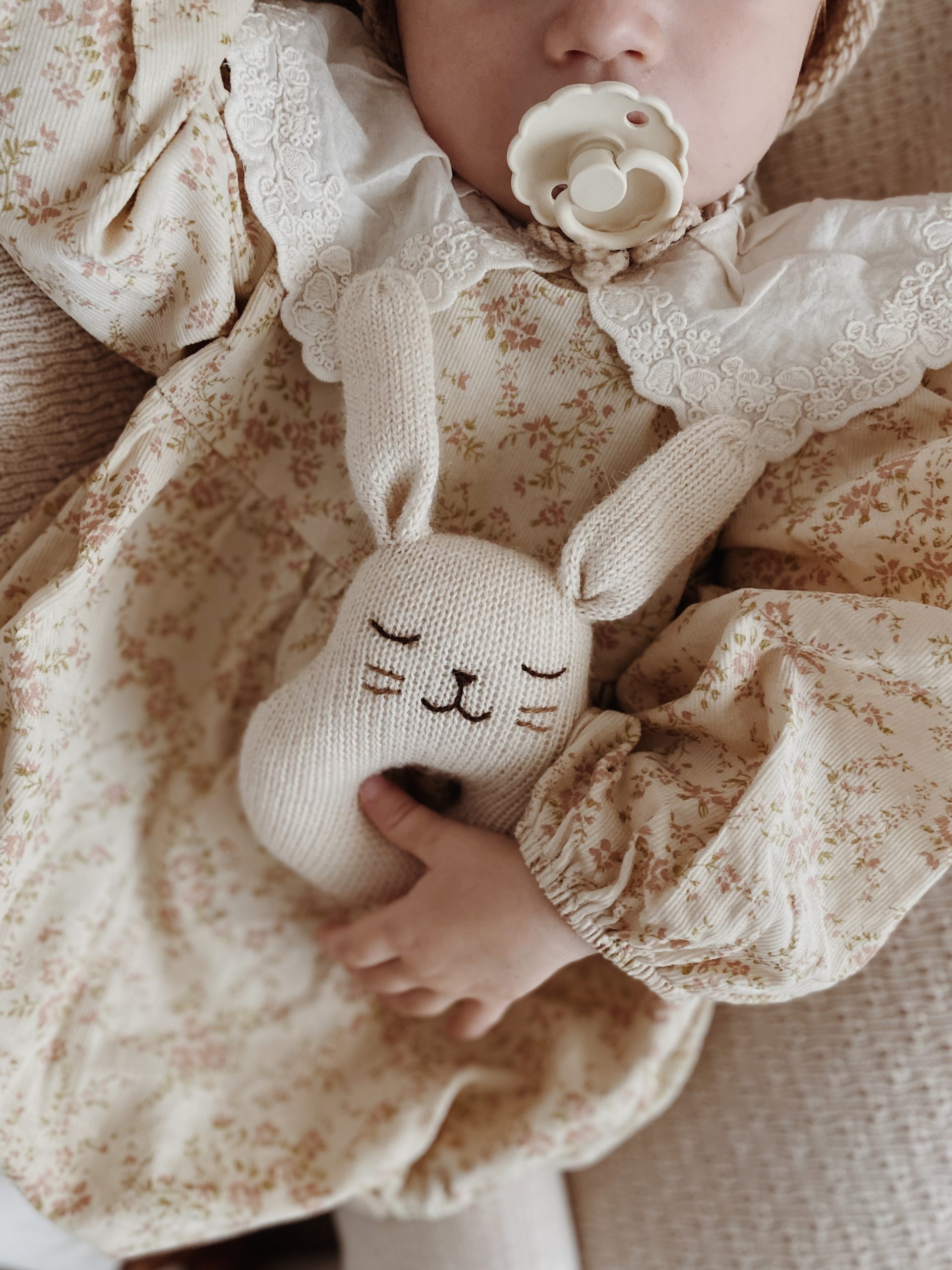 Bébé tenant un hochet en forme de lapin écru en laine tricotée Main Sauvage
