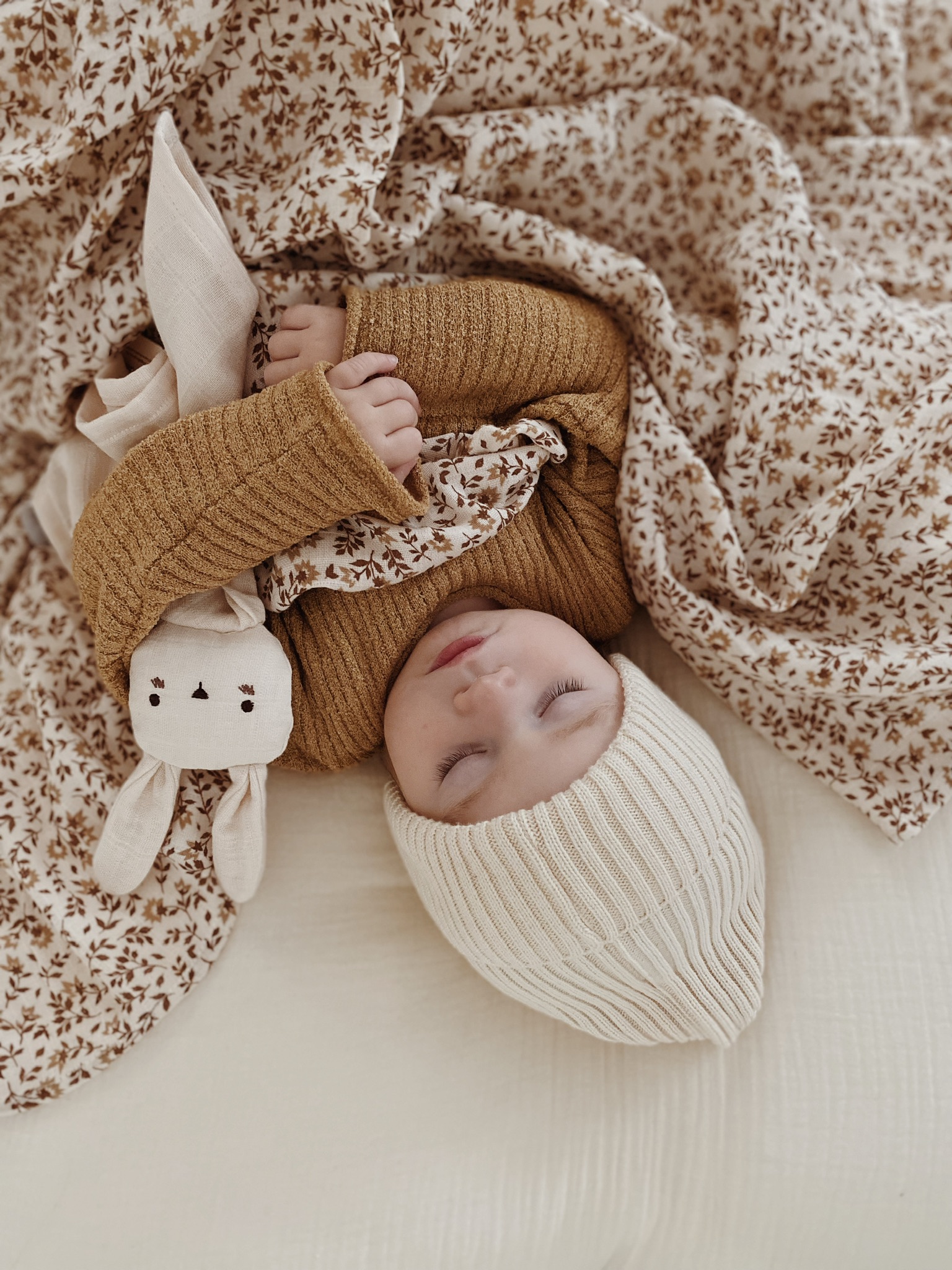 Bébé endormi avec le doudou lange Lapin écru Main Sauvage entre ses bras – image vue du dessus inversée