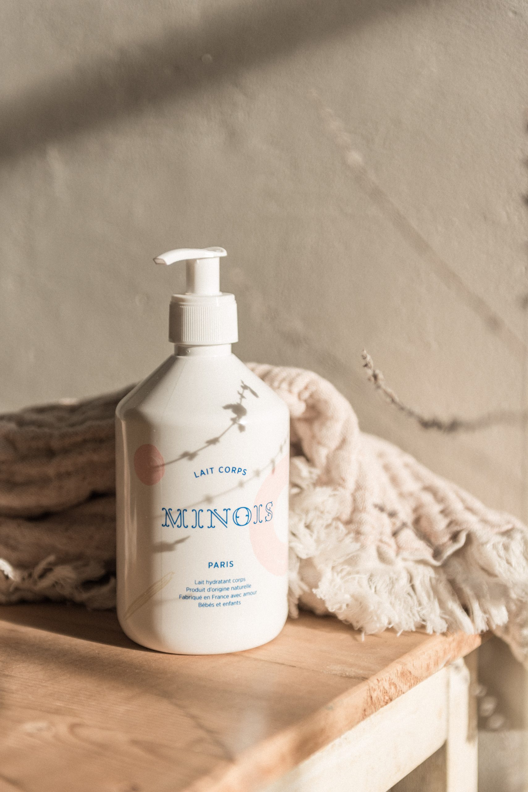 Lait hydratant bébé Minois Paris 500 ml sur plaid beige.