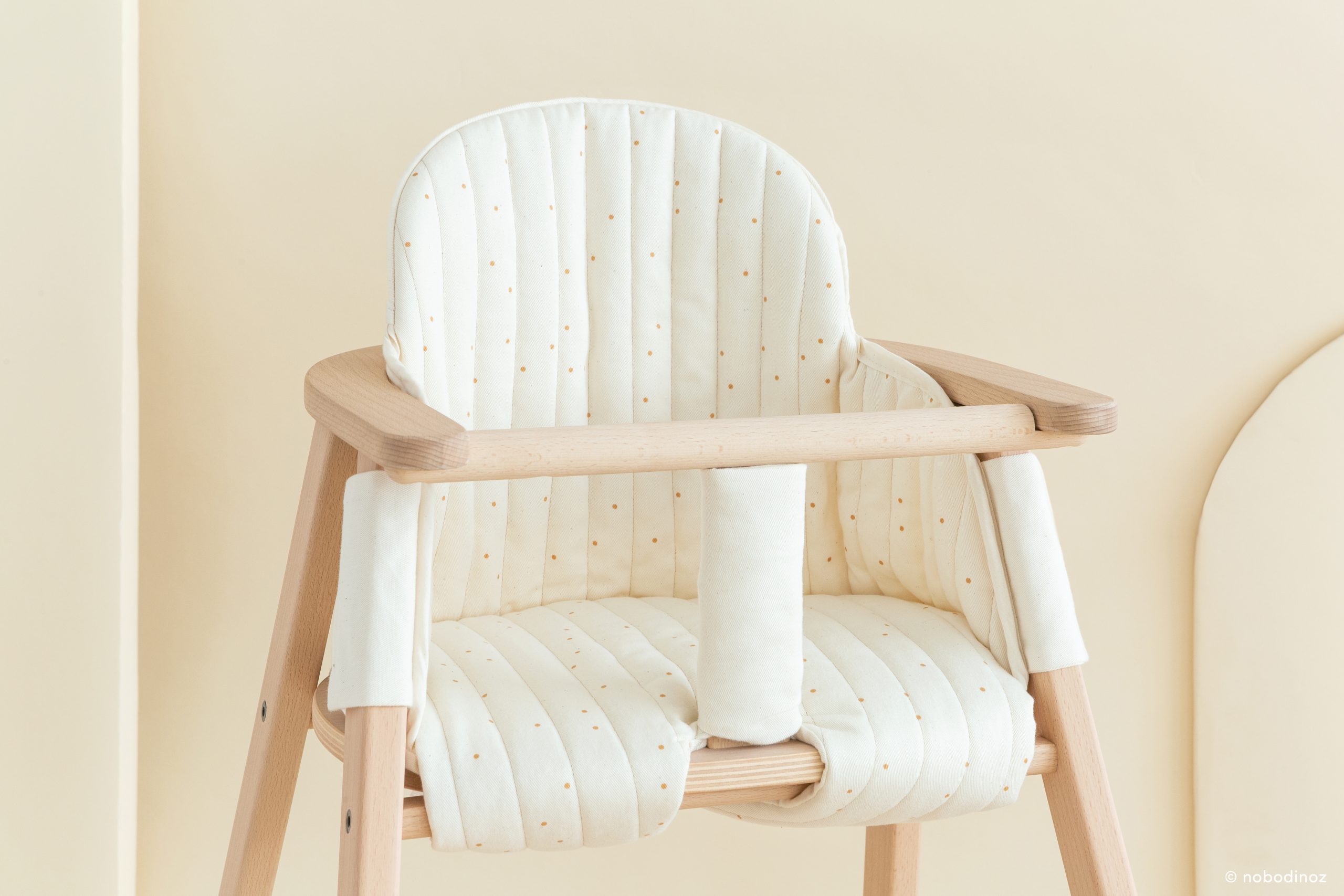 Coussin Nobodinoz Growing Green pour chaise haute, en coton bio, présenté dans une ambiance naturelle et minimaliste.