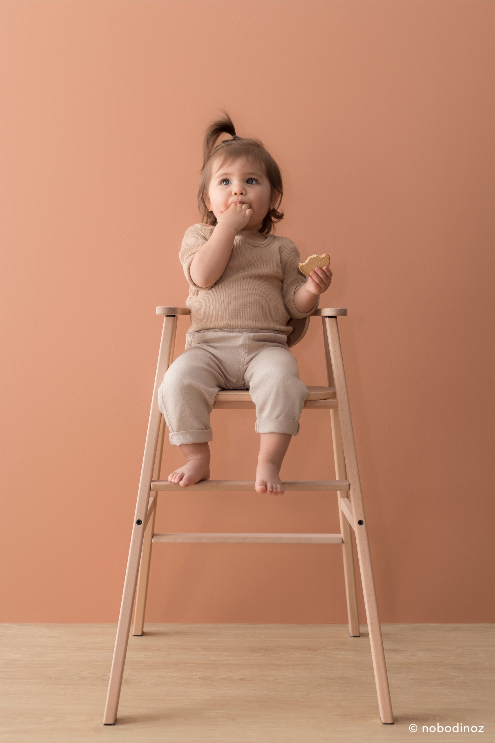 Bébé mangeant sur la chaise haute Nobodinoz Growing Green en bois clair.