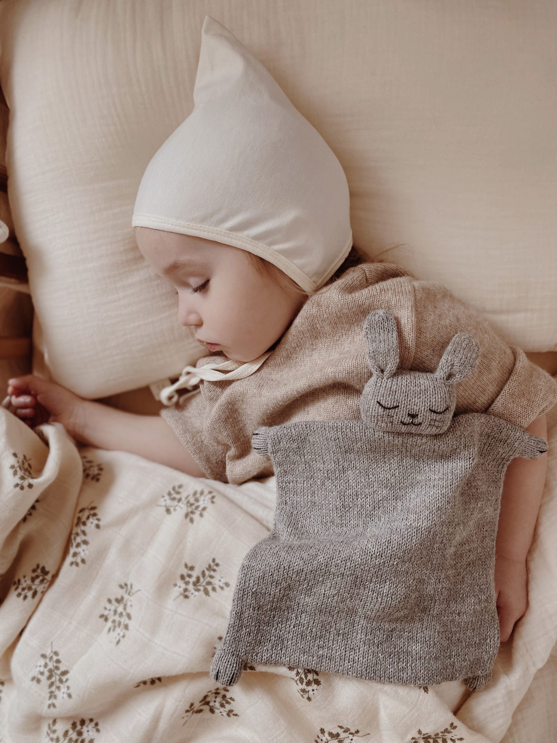 Bébé dormant avec le lange en mousseline de coton Main Sauvage Holly Flowers et un doudou lapin.