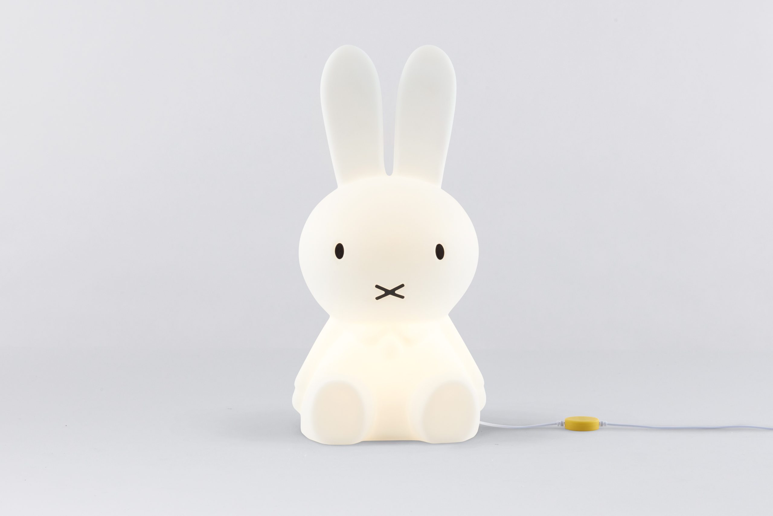 Veilleuse Miffy allumée avec bouton ON/OFF jaune et câble visible sur fond gris