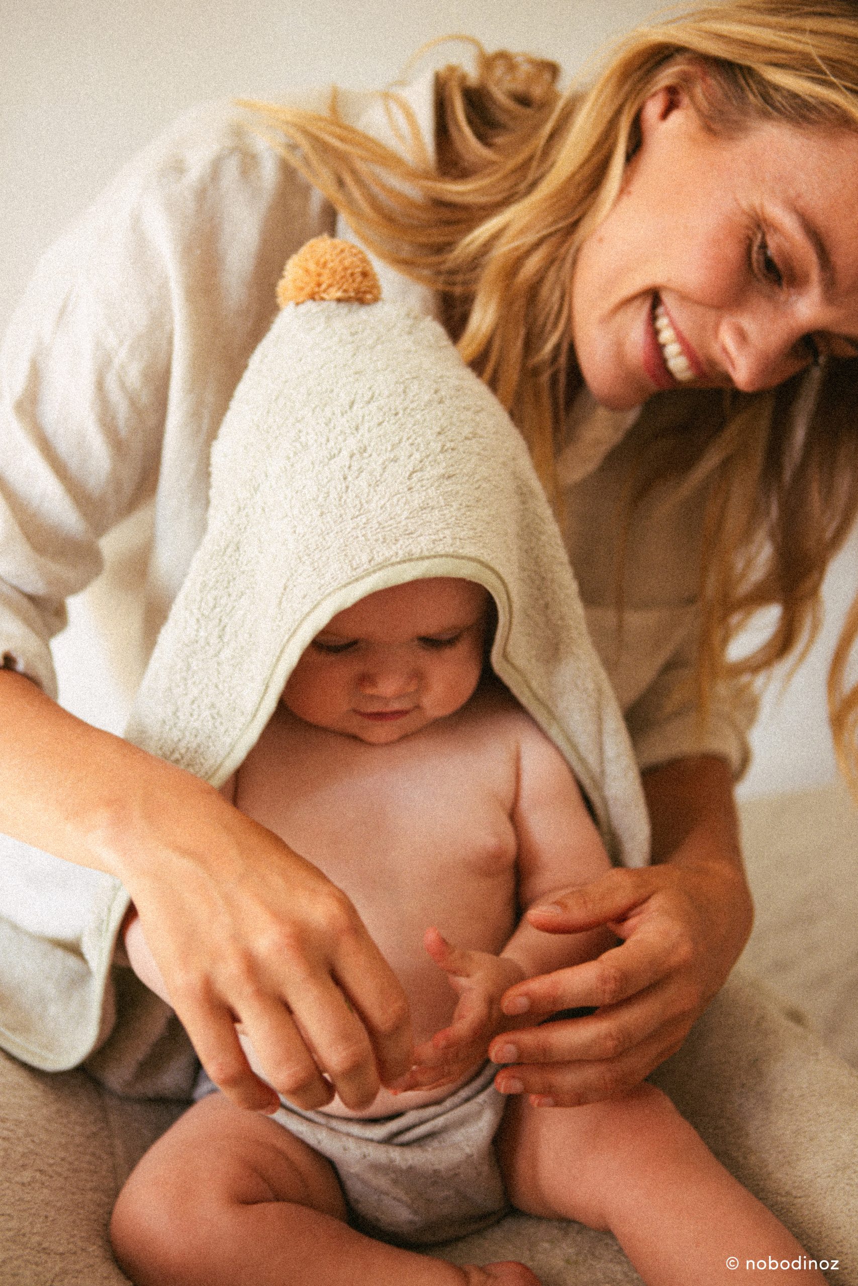 Maman et bébé avec la cape de bain Nobodinoz en coton bio vert sauge.