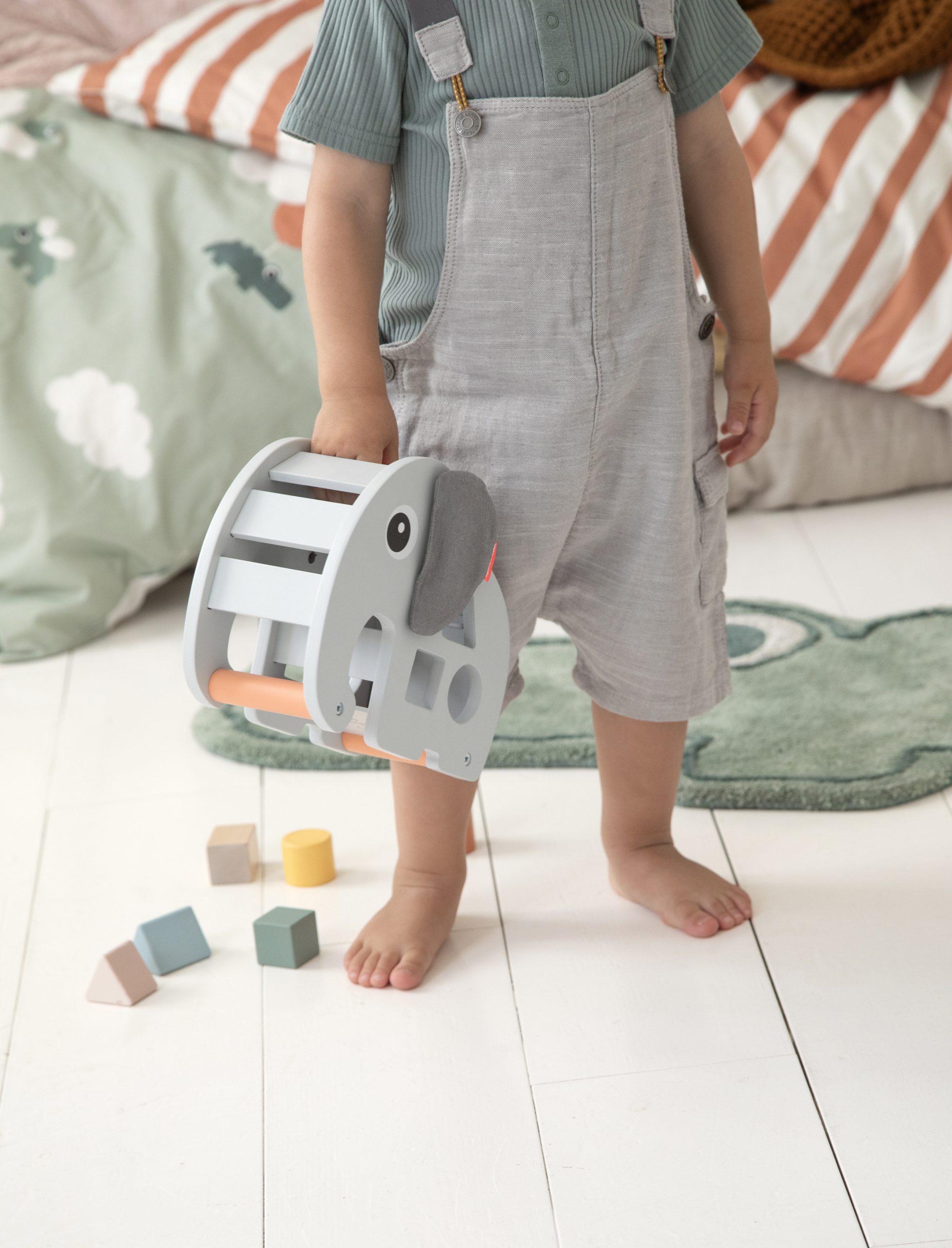 Enfant portant le jeu à encastrer Elphée Done by Deer par la poignée.