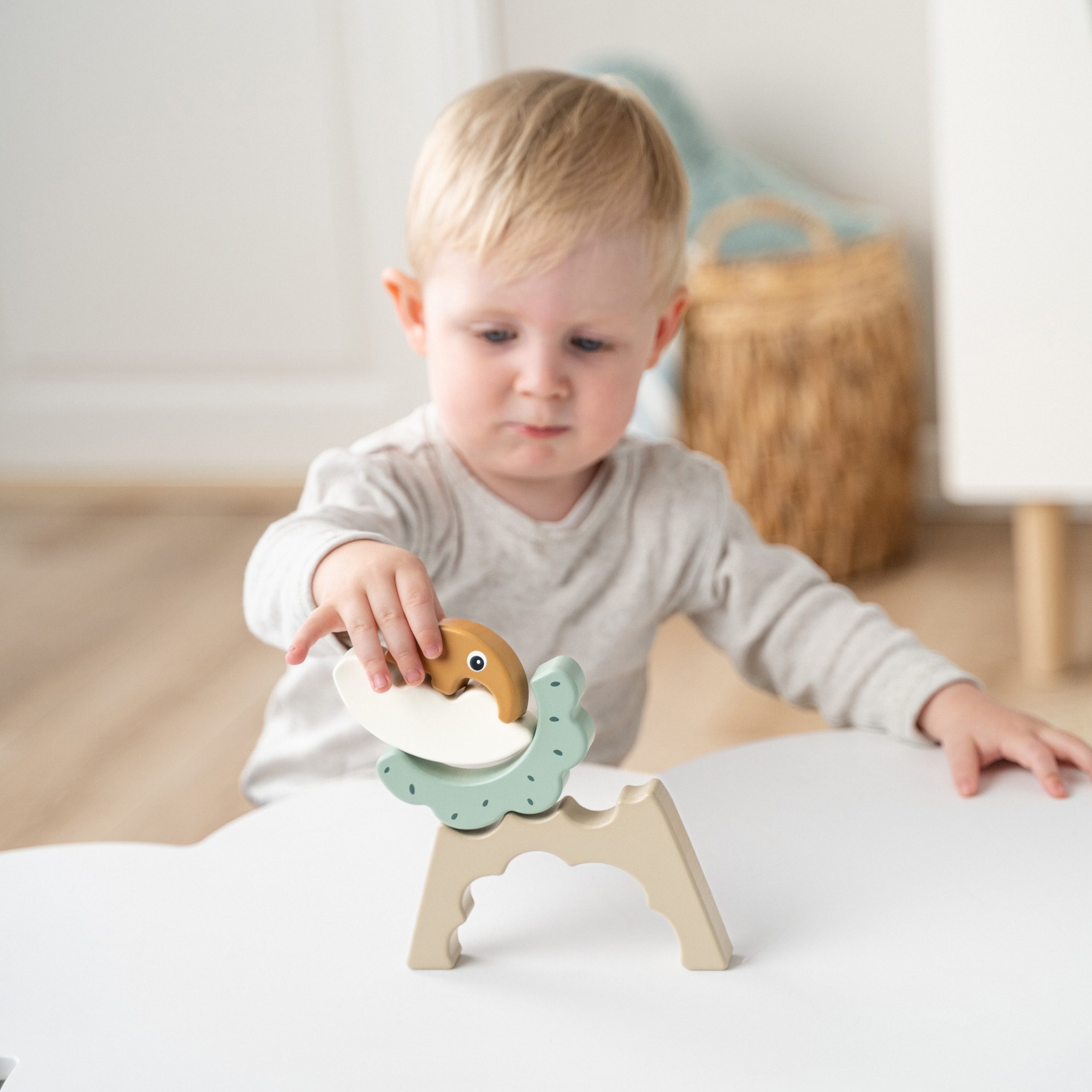 Petit garçon jouant avec l’arc à empiler Antee – Done by Deer – il empile les pièces en bois sur une table – jouet éducatif dès 12 mois
