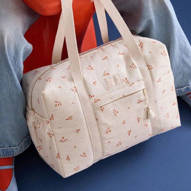 Sac week-end fleuri posé au sol, idéal pour compléter votre liste maternité.