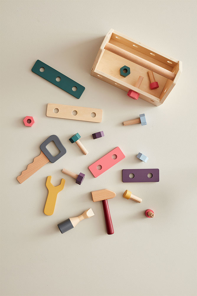 Caisse à outils en bois vide et jouets bricolage disposés autour.