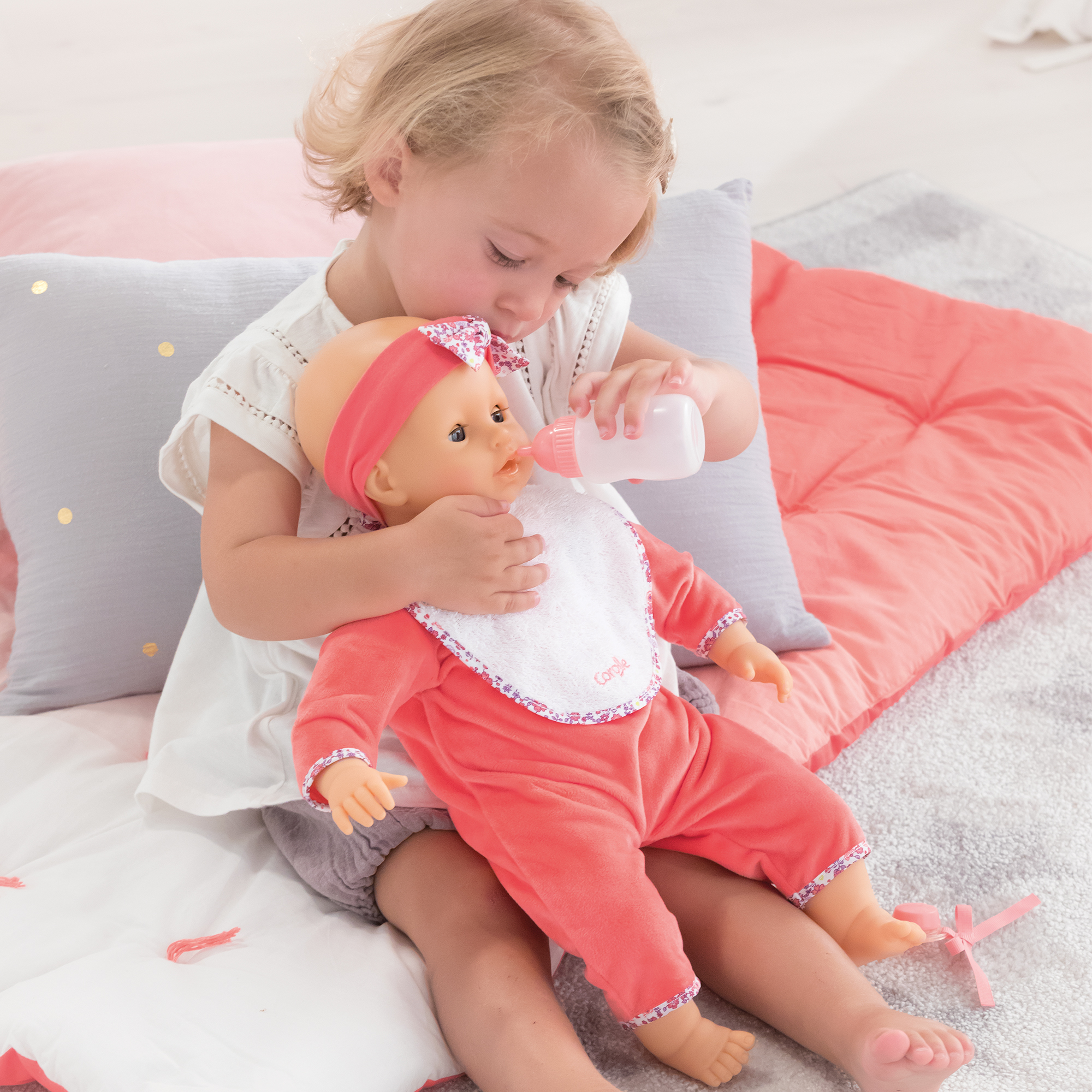Enfant jouant avec le poupon Corolle Lila Chérie et lui donnant le biberon.