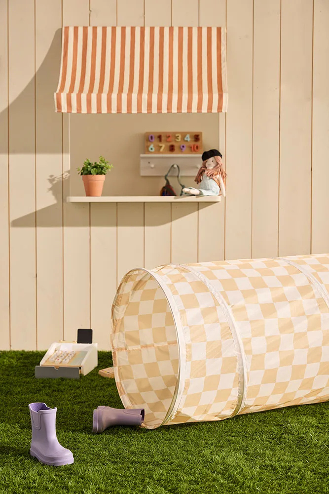 Tunnel de jeu bébé à carreaux jaunes Kid’s Concept installé sur pelouse avec jouets d’extérieur