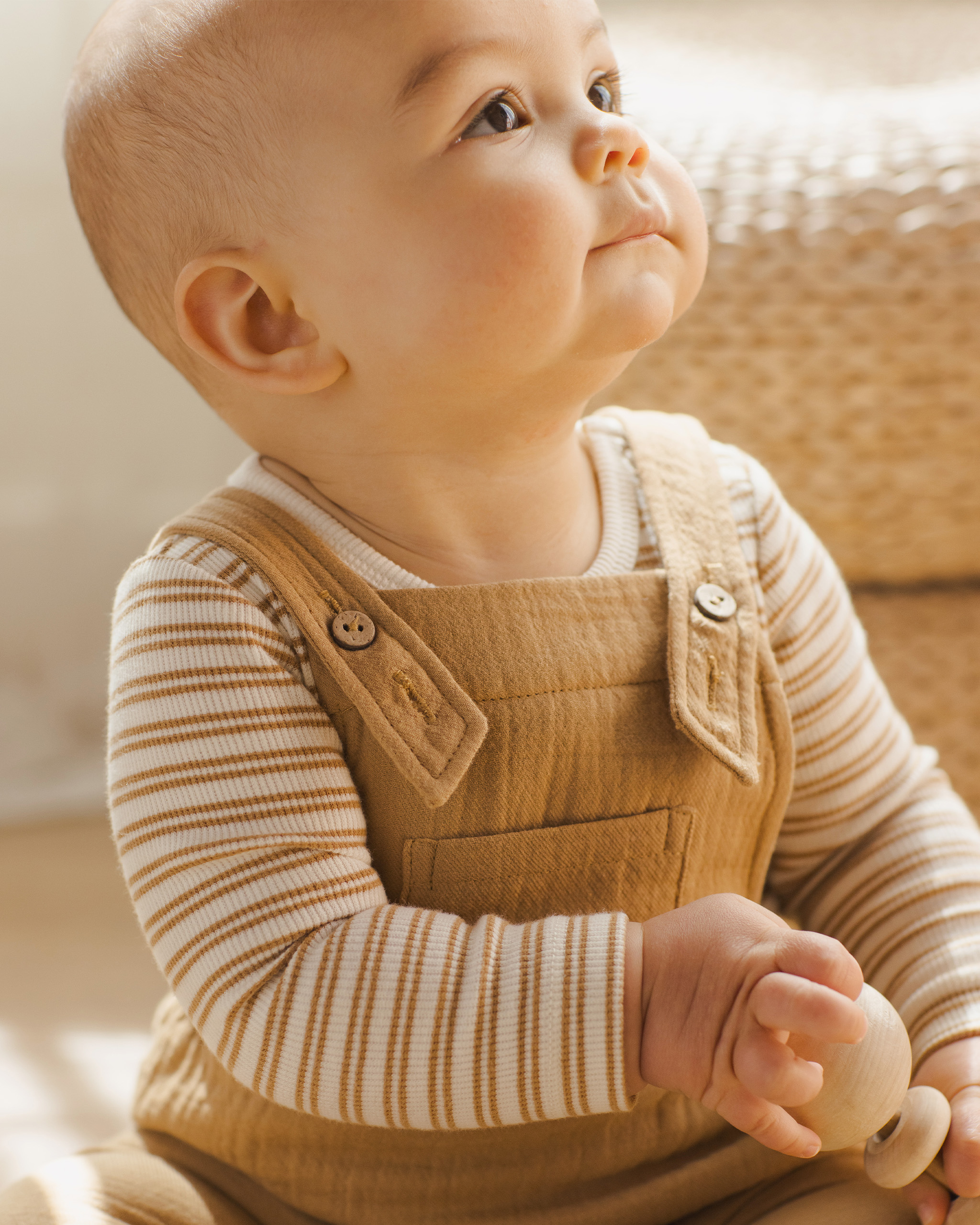 Bébé assis portant un body côtelé Quincy Mae coloris Miel, manches longues, dans une chambre