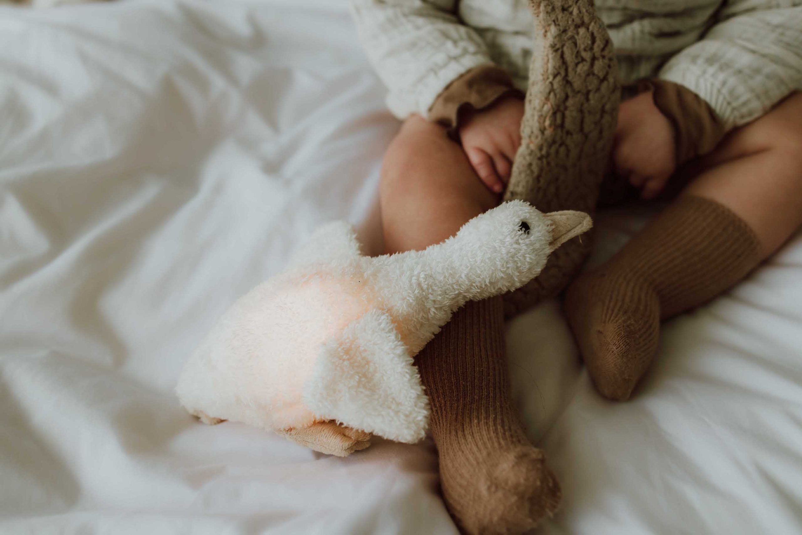 Peluche lumineuse Liva posée près d’un bébé sur le lit