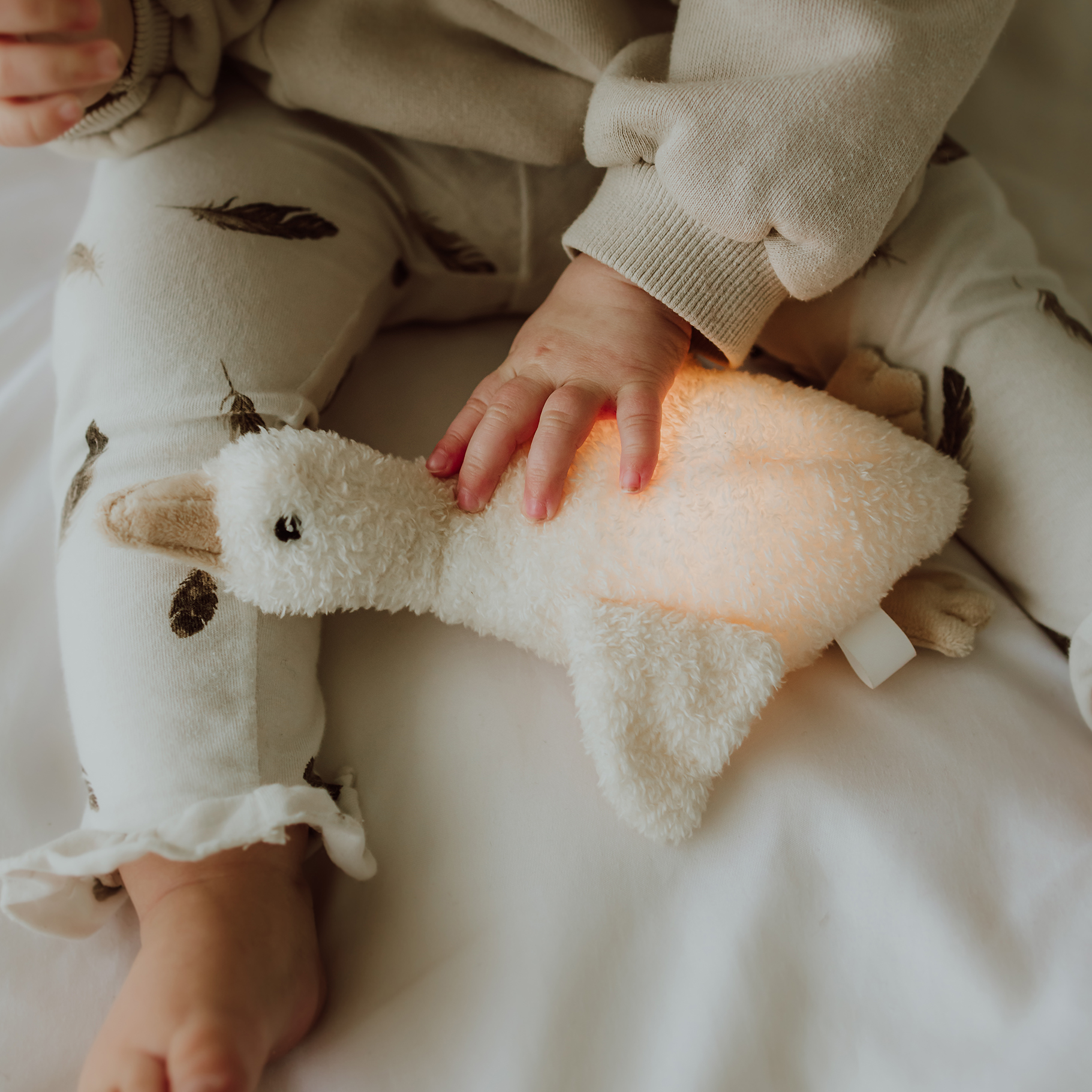 Bébé tenant la peluche lumineuse Liva allumée pour s’endormir