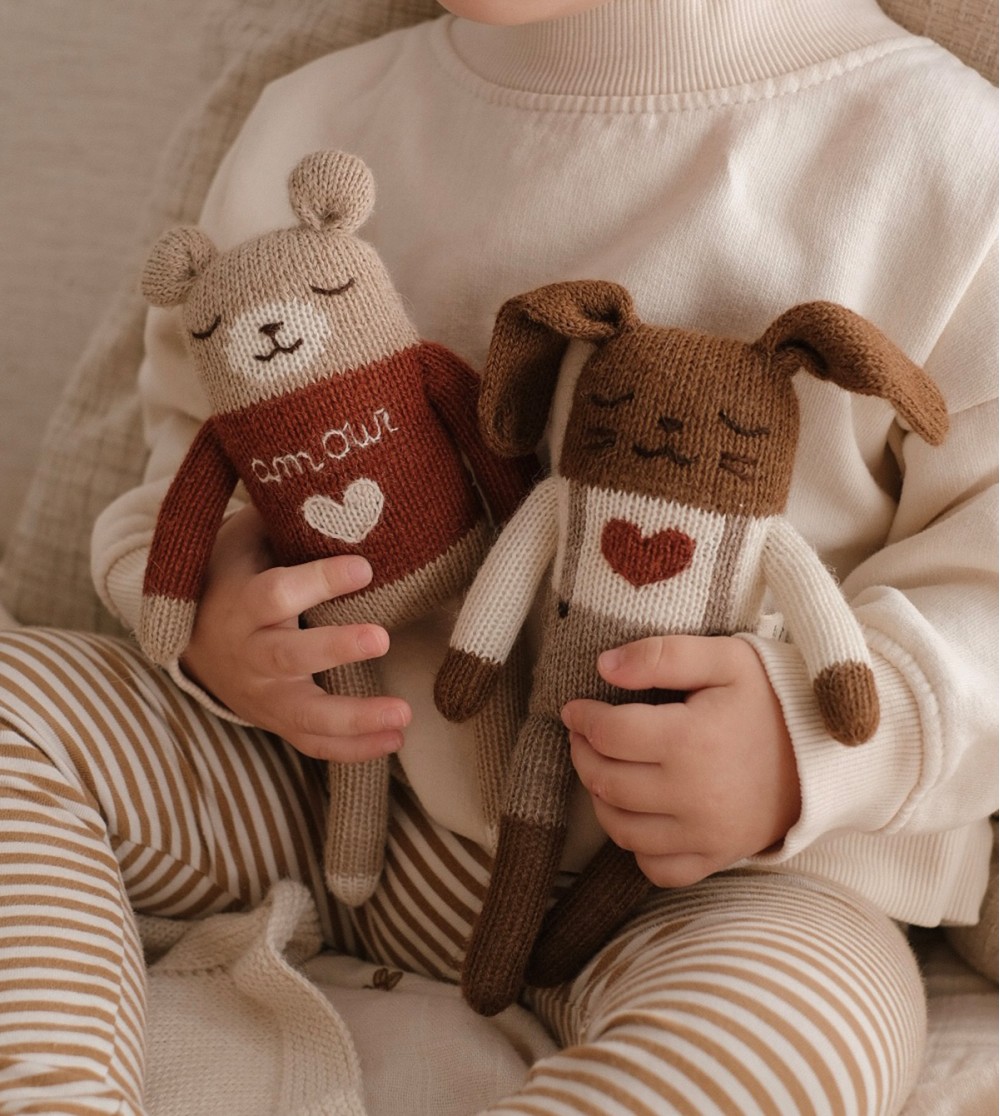 Enfant tenant dans ses mains les doudous Lapin Amour et Ourson Amour Main Sauvage – moment réconfortant