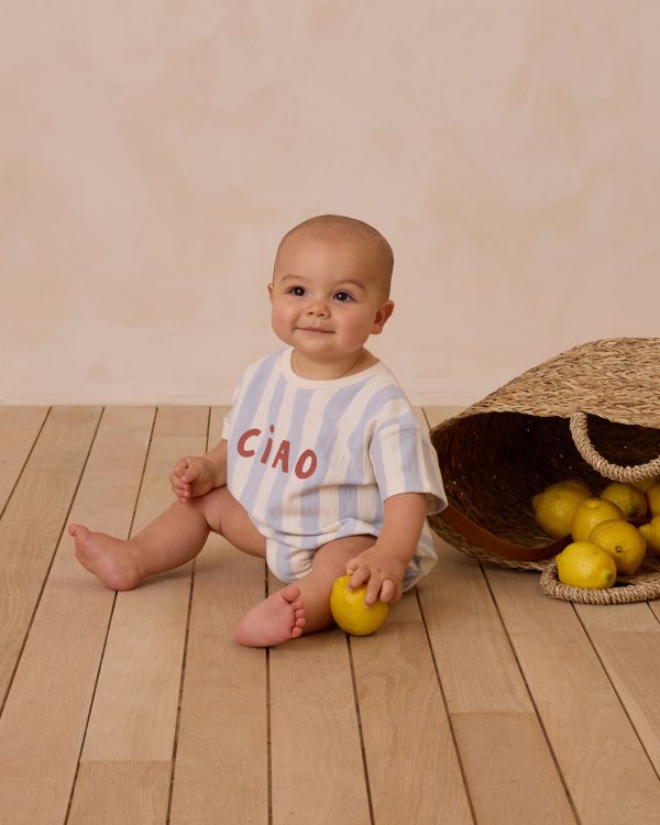 Bébé assis portant une combinaison à rayures bleu clair Rylee + Cru avec l’inscription "Ciao", assis près d’un panier de citrons.