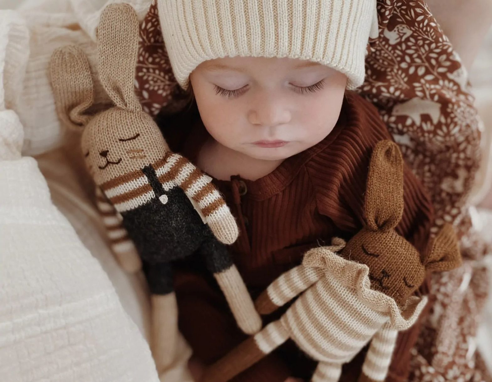 Bébé endormi avec deux doudous tricotés dans les bras