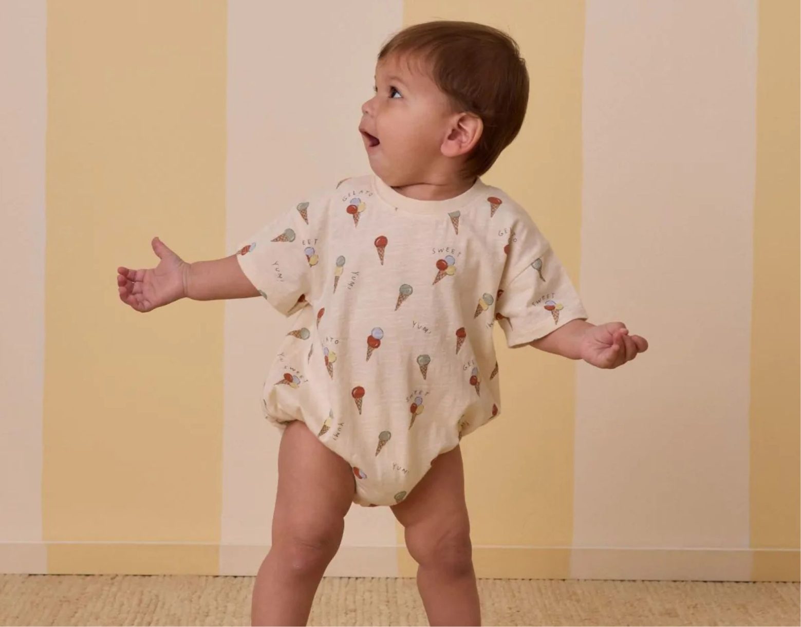 Bébé portant la combinaison à bulles Rylee + Cru imprimée glaces, coupe bouffante et fond ivoire