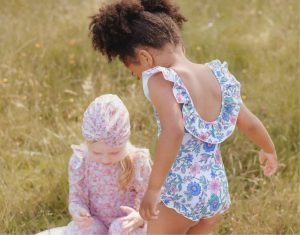 Enfant portant le maillot 1 pièce Louise Misha à fleurs bleues et roses, avec volants aux épaules