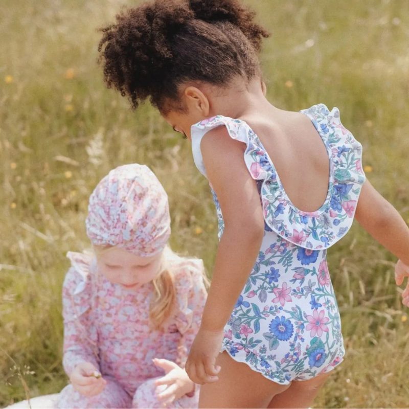 Enfant portant le maillot 1 pièce Louise Misha à fleurs bleues et roses, avec volants aux épaules