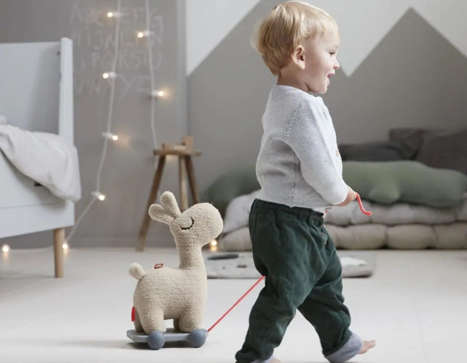 Enfant qui tire un jouet lama en tissu dans une chambre enfant chaleureuse
