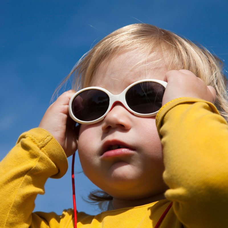 Bébé en haut jaune portant des lunettes de soleil blanches par temps ensoleillé