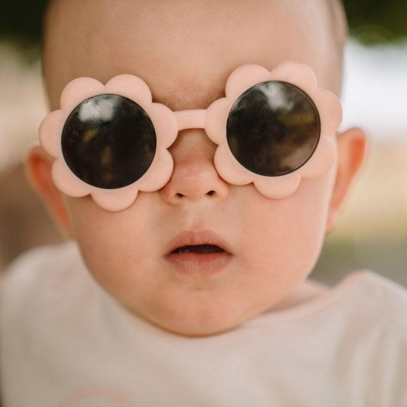 Bébé avec des lunettes de soleil roses en forme de fleur