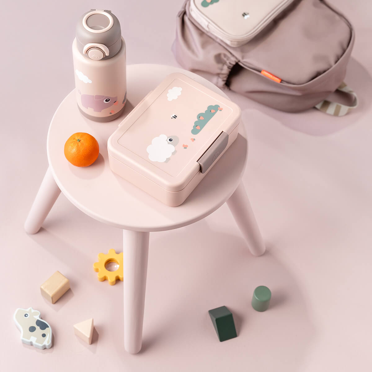 Boîte à goûter rose enfant avec mouton et gourde assortie Done by Deer posées sur une table