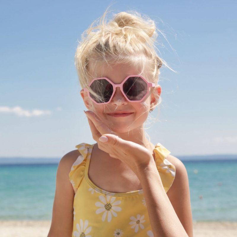 Petite fille avec des lunettes de soleil roses sur la plage