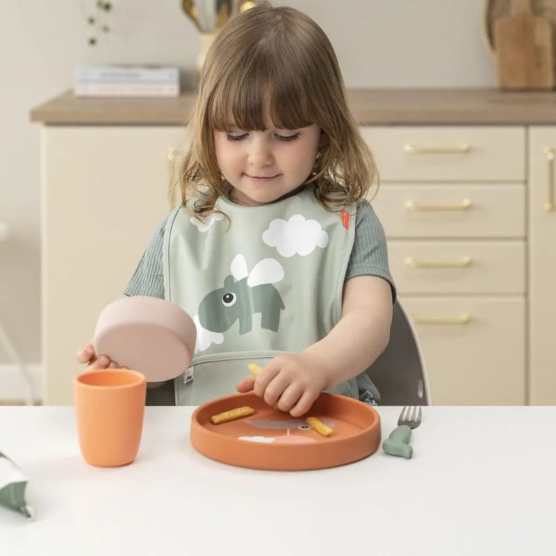 Petite fille mange seule avec une assiette en silicone et une tasse, durant sa diversification alimentaire