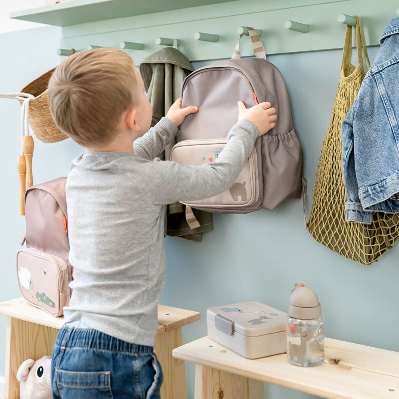 Préparer la rentrée en maternelle : enfant accrochant un sac à dos Done By Deer dans un vestiaire d’école