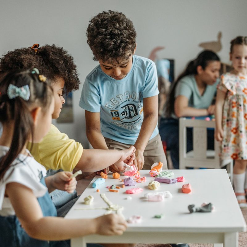 Groupe d’enfants partageant de la pâte à modeler colorée lors d’un atelier créatif à l’école.