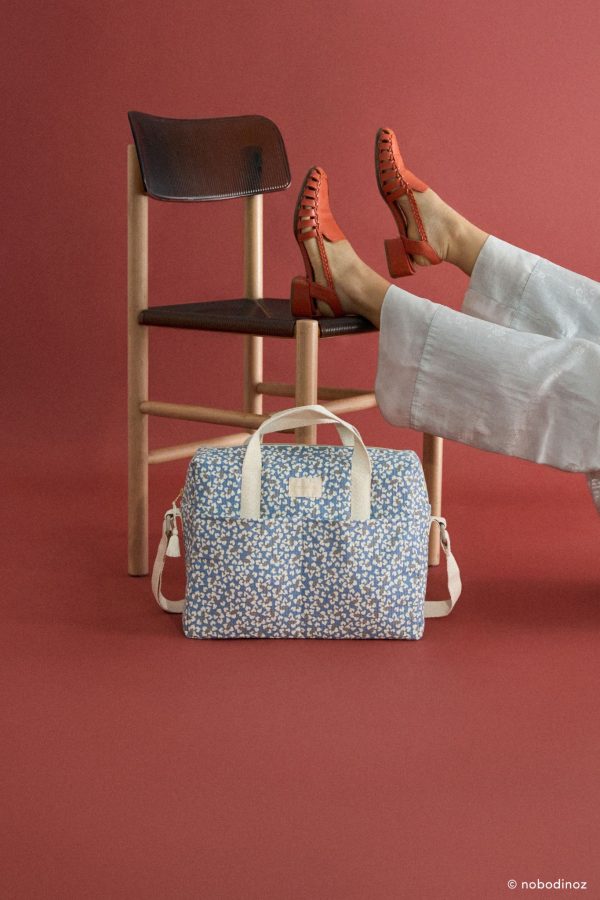 Sac à langer Nobodinoz Gala Opéra Blue Yumiko posé au sol à côté d’une chaise, style moderne