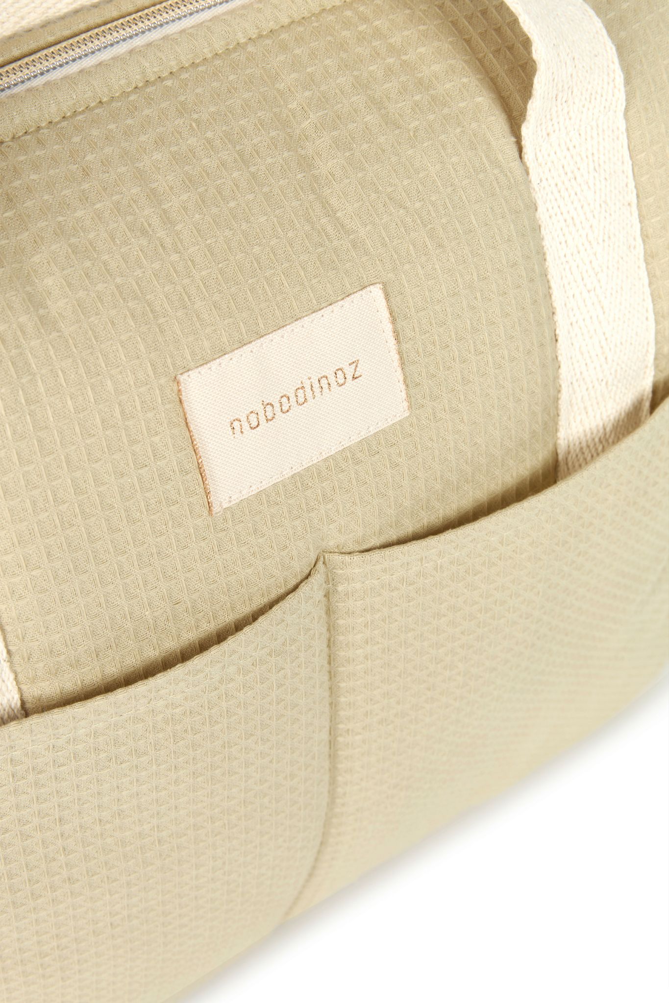 Détail du logo brodé et du tissu vert d'eau du sac à langer Nobodinoz Gala Opera