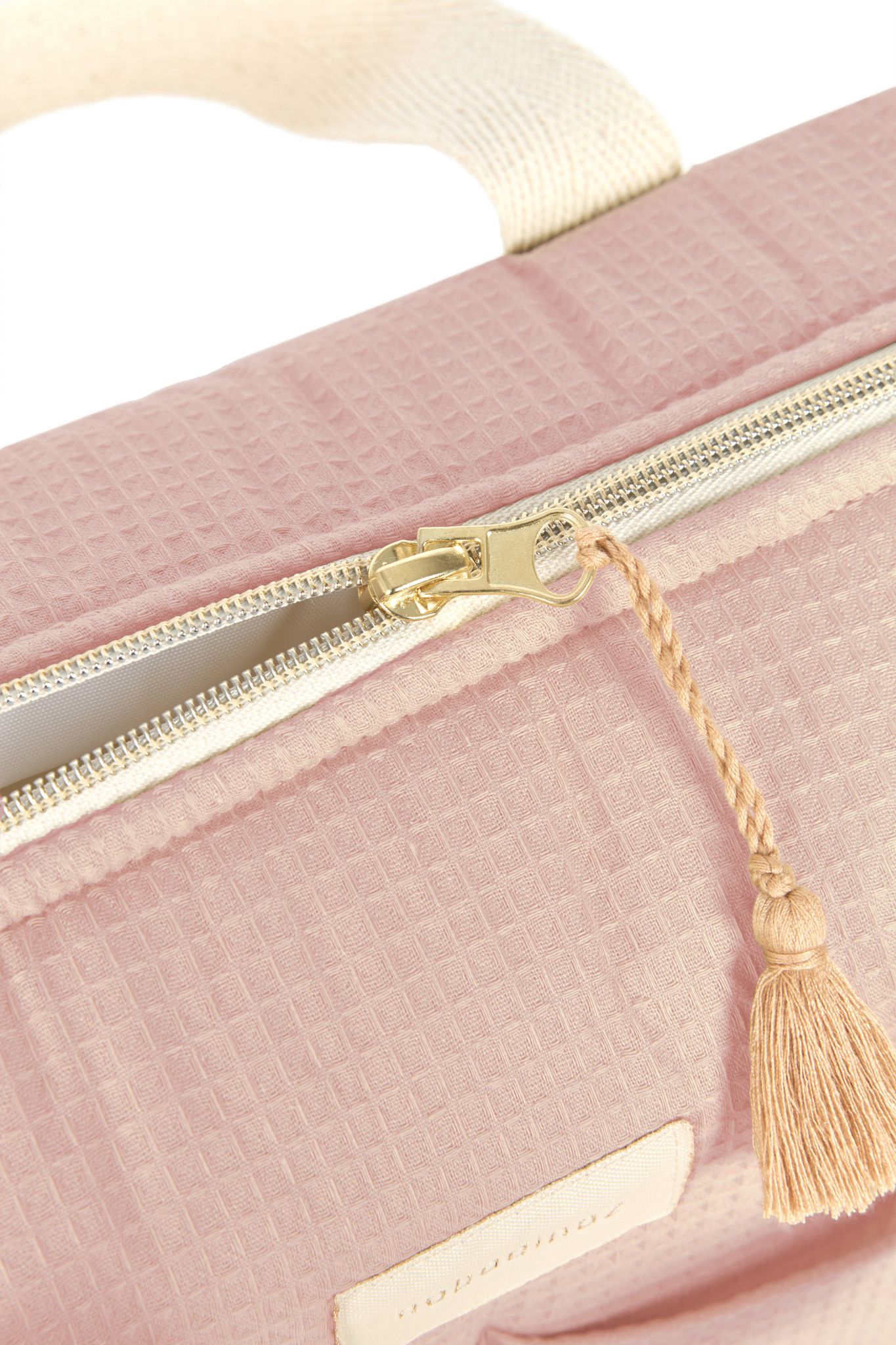 Gros plan sur la fermeture éclair et la pampille en coton bio du sac à langer Nobodinoz rose pâle