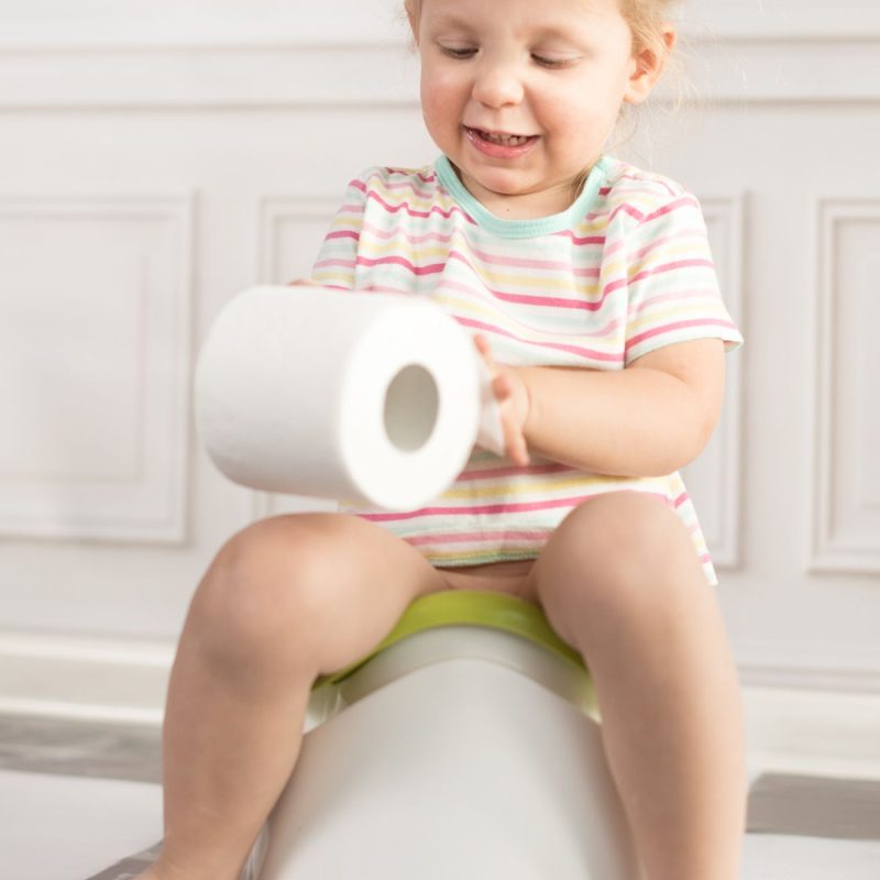 Bébé assis sur pot blanc avec papier toilette – apprentissage de la propreté.