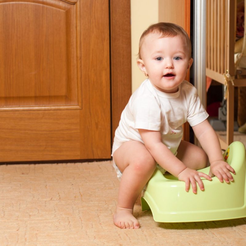 Bébé assis sur un pot vert – apprentissage de la propreté à la maison.