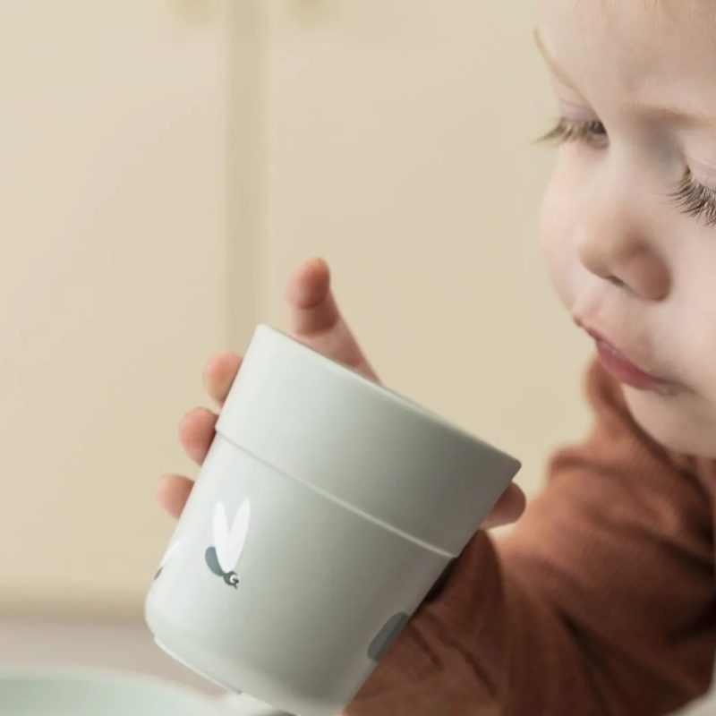 Enfant de 2 ans qui boit seul dans une tasse adaptée