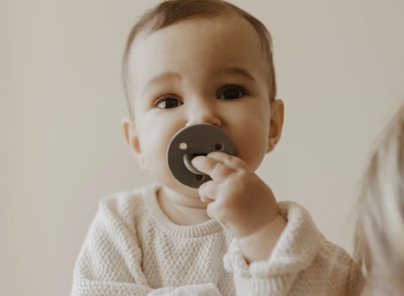 Bébé portant une sucette Élhée kaki et jouant avec la tétine