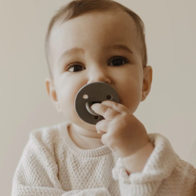 Bébé portant une sucette Élhée kaki et jouant avec la tétine