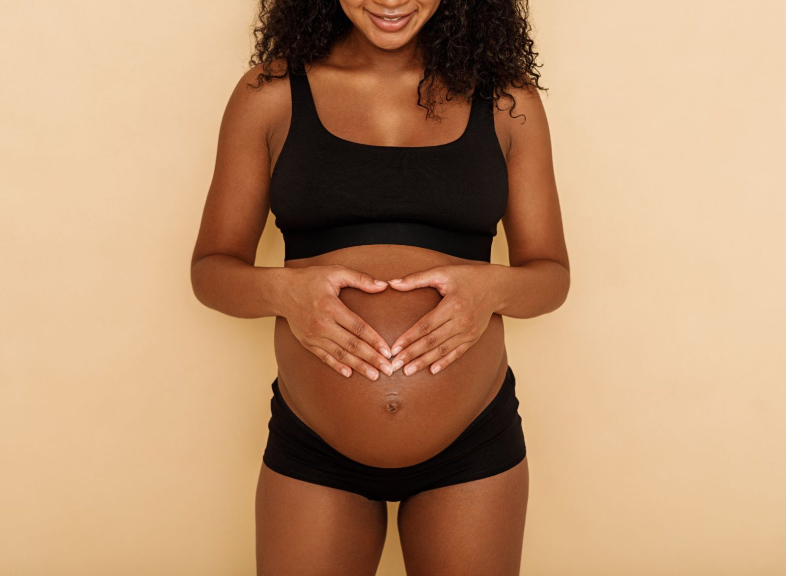 Femme enceinte formant un cœur avec ses mains sur son ventre, illustrant la préparation de la liste de naissance à Montpellier.