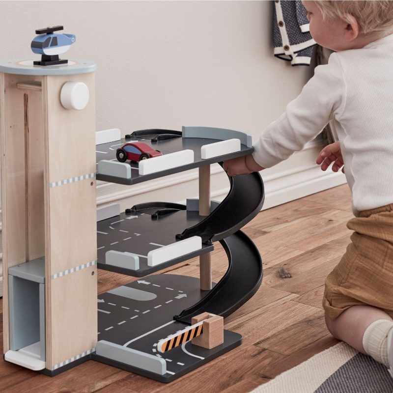 Enfant jouant avec un parking en bois Kid's Concept avec voitures et hélicoptère – idée cadeau Noël bébé et jouet d’imitation