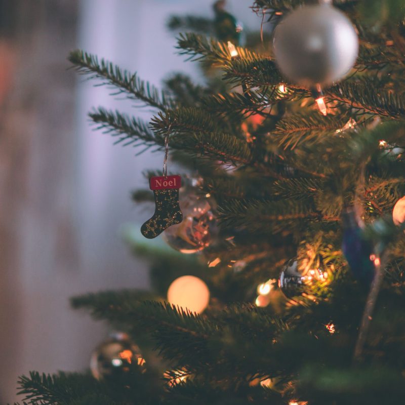 Sapin de Noël décoré avec lumières et chausson festif, créant une atmosphère chaleureuse avant un repas femme enceinte Noël.