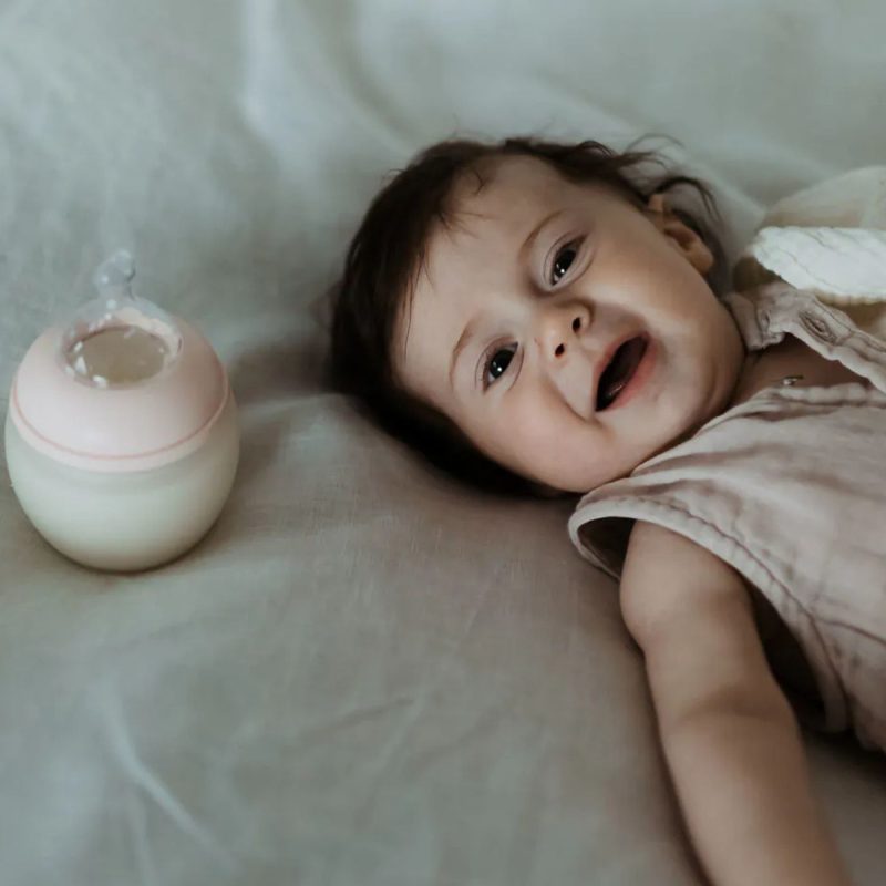 Bébé allongé avec un biberon de lait infantile dans un contexte d’allaitement mixte.