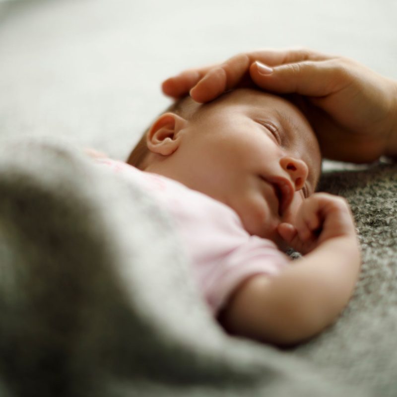 Bébé endormi et apaisé grâce au réconfort d’un parent en cas de colique du nourrisson