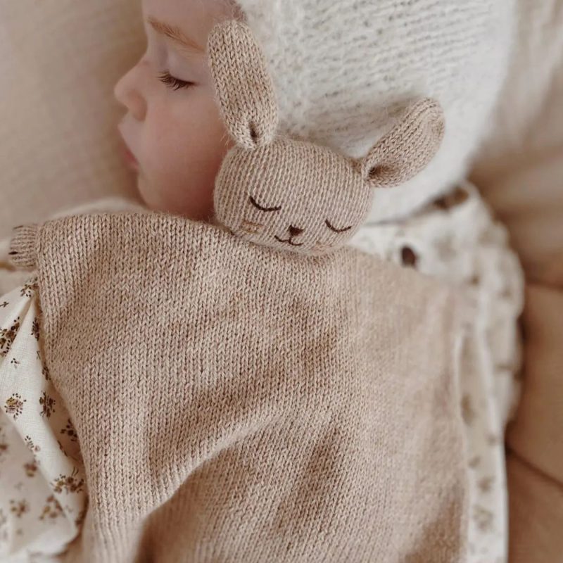 Bébé dormant avec un doudous lapin en maille beige contre lui