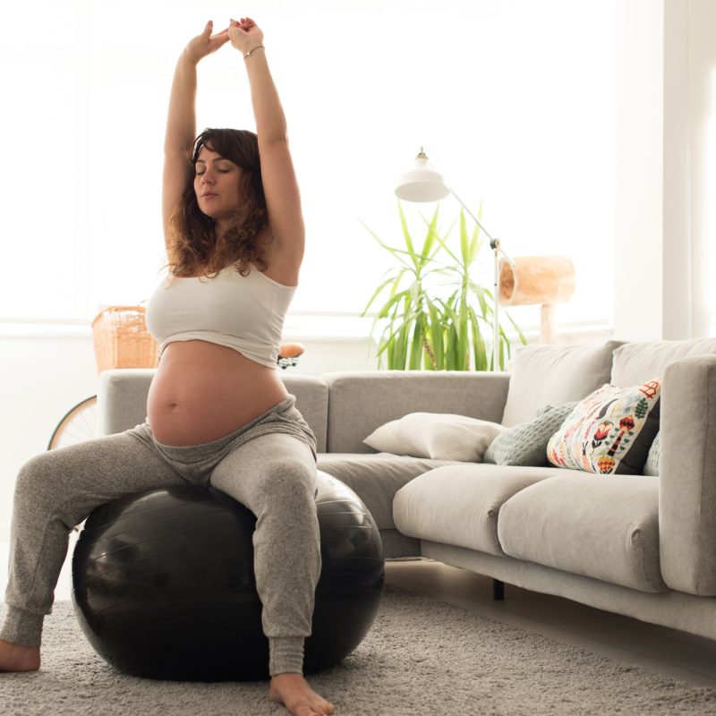 Femme enceinte faisant des exercices adaptés pendant la grossesse à la maison