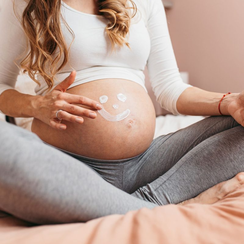 Femme enceinte appliquant une crème sur son ventre pendant les semaines d’aménorrhée